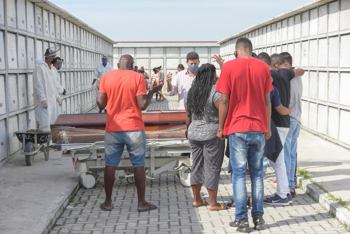 Pessoas velando um corpo em local isolado devido à pandemia de covid-19