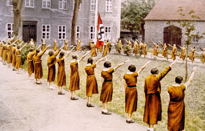 Jovens alemães fazendo saudação nazista em pátio de escola.