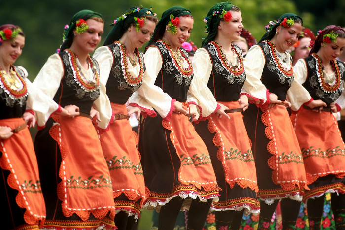 Pessoas em trajes tradicionais dançando horo búlgaro perto da aldeia de Varvara, na Bulgária.