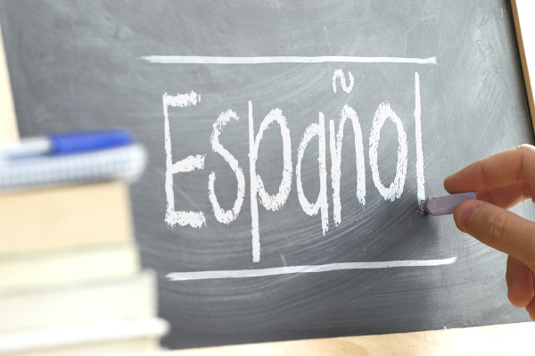 Pessoa escreve em quadro-negro a palavra “Español”.