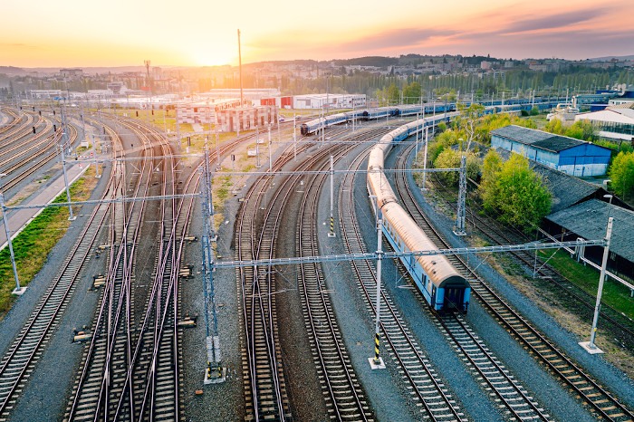 Vista aérea de uma estação ferroviária com vagões de trem e ênfase no nascer do Sol.