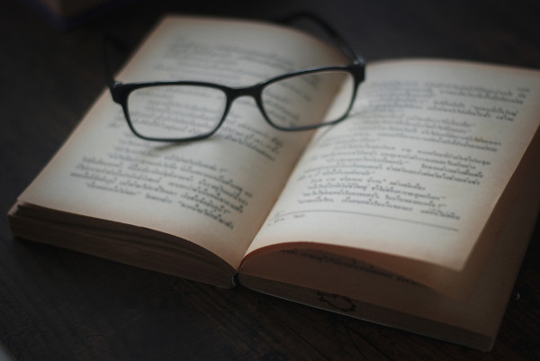 Óculos de leitura sobre página de livro aberto