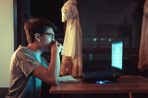 Jovem estudante olhando fixamente para tela de computador.