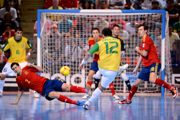 Jogador Falcão de costas chutando bola em jogo de futsal.