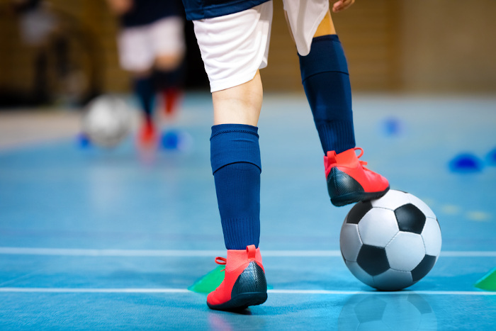 Pés de praticante de futsal e uma bola. 