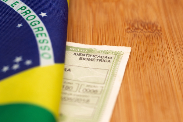 Bandeira do Brasil dobrada sobre um título do eleitor, um documento necessário às eleições do primeiro e do segundo turno.