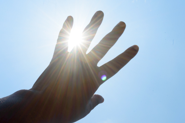 Mão sendo exposta a luz solar, recebendo radiação ultravioleta.