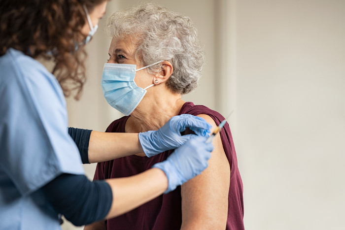 Enfermeira aplicando vacina no braço de uma pessoa idosa, uma forma de fortalecer o sistema imunológico.