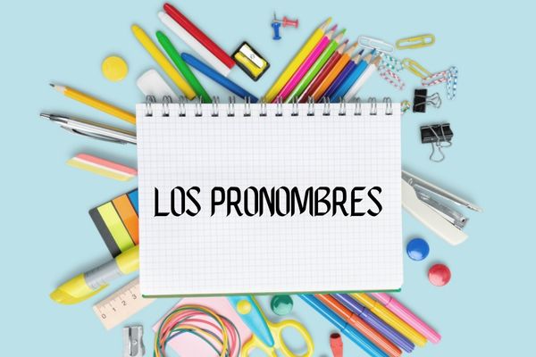 Caderno com o escrito “los pronombres” (os pronomes em espanhol) sobre vários objetos escolares.