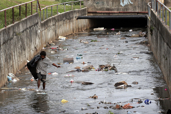 Catador de materiais recicláveis em um córrego poluído, uma das consequências da pobreza no Brasil.