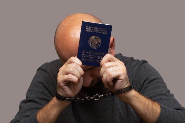 Imagem de homem com as mãos algemadas cobrindo o rosto e segurando um passaporte representando o ato de extradição.