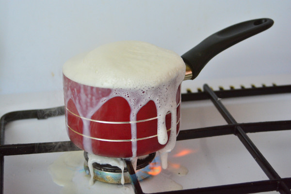 Leite transbordando em uma panela e derramando no fogão após ser aquecido, um exemplo de dilatação volumétrica.