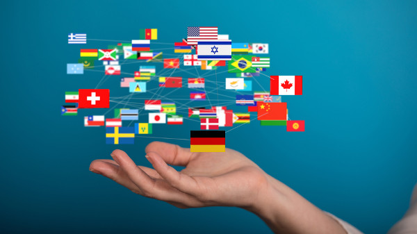 Pessoa com a mão sob uma ilustração de várias bandeiras interligadas, representando a mundialização.