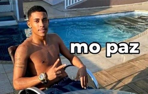 Mc Poze, homem negro, está sem camisa e de bermuda ao lado de uma piscina. Texto: “mo paz”.