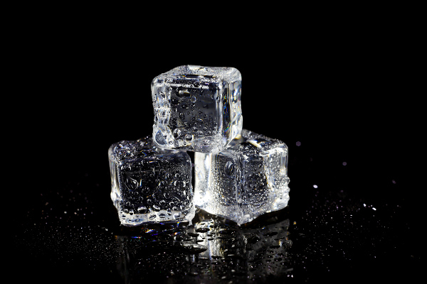 Três cubos de gelo sobre uma superfície lisa.