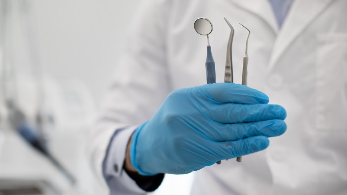 Dentista segurando utensílios odontológicos feitos de aço inoxidável aditivado com molibdênio.