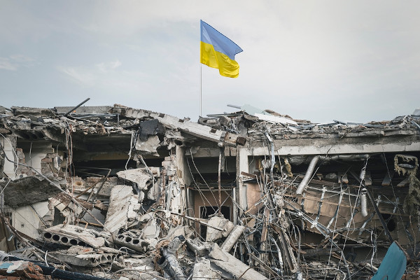 Bandeira ucraniana sobre os destroços em uma região bombardeada como representação da guerra entre Rússia e Ucrânia.