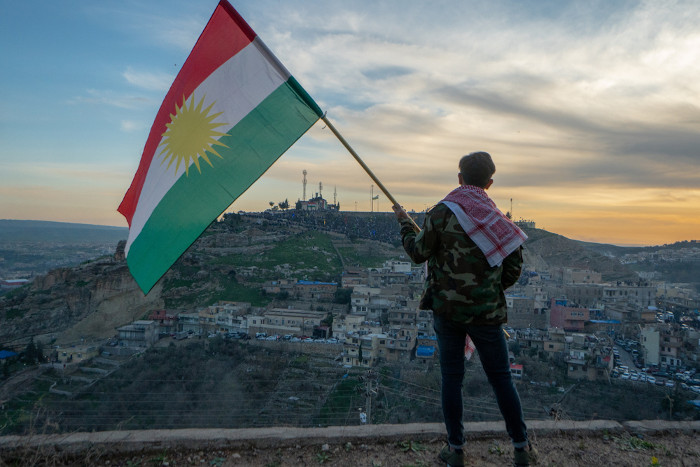 Adolescente segurando a bandeira do Curdistão no norte do Iraque como representação de uma nação que não possui Estado.