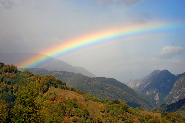 Paisagem natural montanhosa com a presença de um arco-íris.
