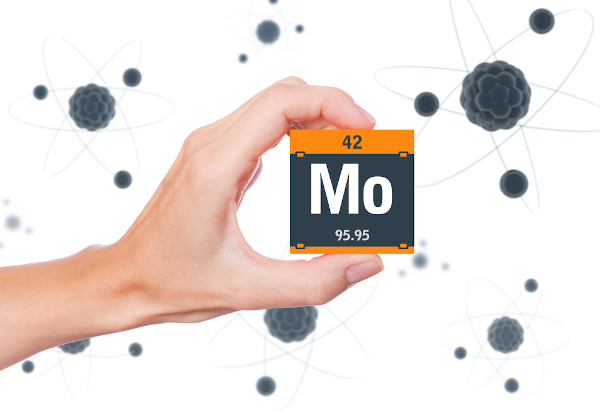 Pessoa segurando um cubo preto com laranja com o símbolo, o número atômico e a massa do elemento químico molibdênio.