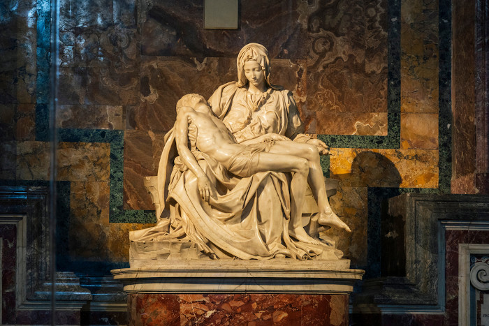  Escultura de uma mulher, a Virgem Maria, segurando o corpo morto de Jesus em seu colo.