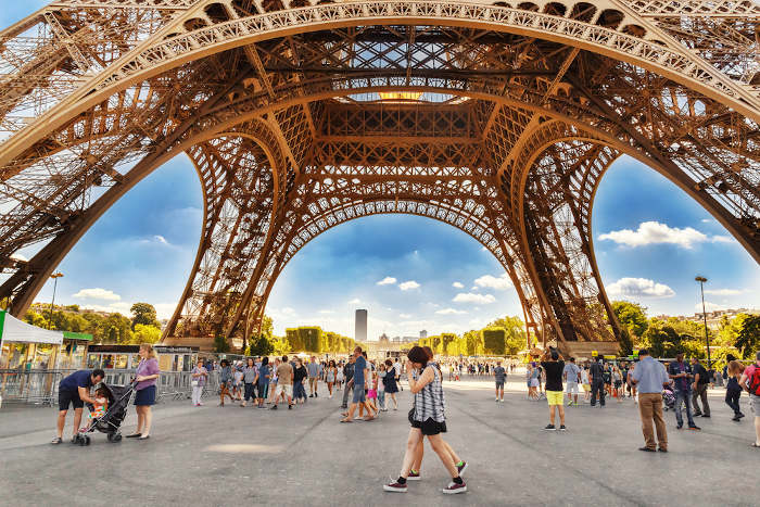 Vários turistas em frente à Torre Eiffel, que recebe milhões de turistas ao longo do ano. 