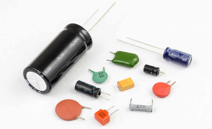 Vários tipos de capacitores sobre uma mesa branca como representação de que o tântalo é utilizado em capacitores.