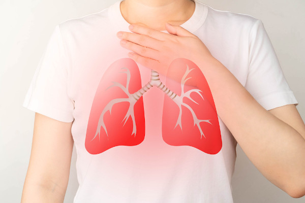 Ilustração de pulmões na silhueta de uma pessoa com a mão no peito, em alusão à falta de ar causada pelo broncoespasmo.