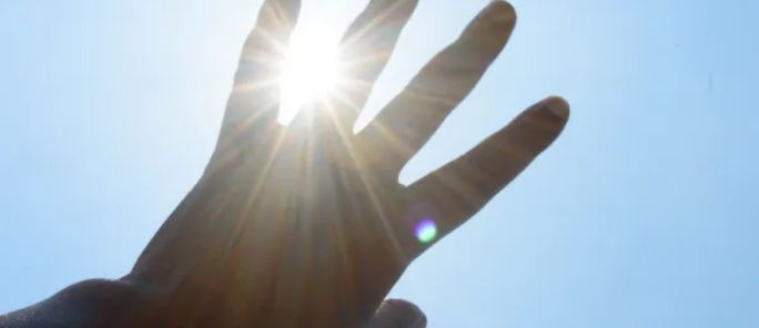 pessoa tampando o sol com a mão