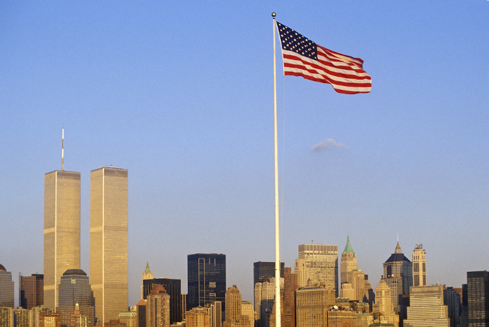 Bandeira dos Estados Unidos hasteada em Nova York, com o World Trade Center, ainda com as “Torres Gêmeas”, ao fundo.