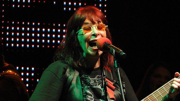 Rita Lee cantando e tocando guitarra.