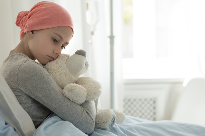 Menina usando um lenço na cabeça, diagnosticada com câncer ainda na infância, um sinal clássico da síndrome de Li-Fraumeni.