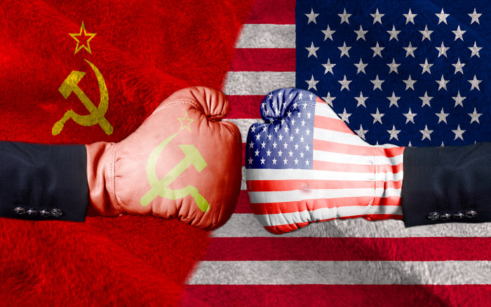 Luvas de boxe com as bandeiras da URSS e dos EUA em oposição, uma representação do conflito que culminou na Guerra Fria.