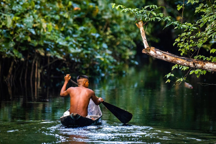 Indígena navegando no Rio Amazonas como representação da Amazônia, um dos biomas brasileiros.