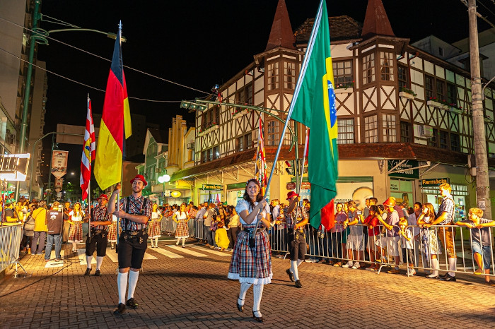 Pessoas desfilando com bandeiras na Oktoberfest, exemplo da diversidade cultural no Brasil.
