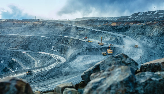 Escavadeiras trabalhando em um poço de mineração, atividade que causa impactos ambientais.