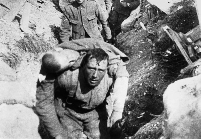 A imagem mostra um soldado britânico ferido durante a Batalha do Somme sendo carregado através de uma trincheira.