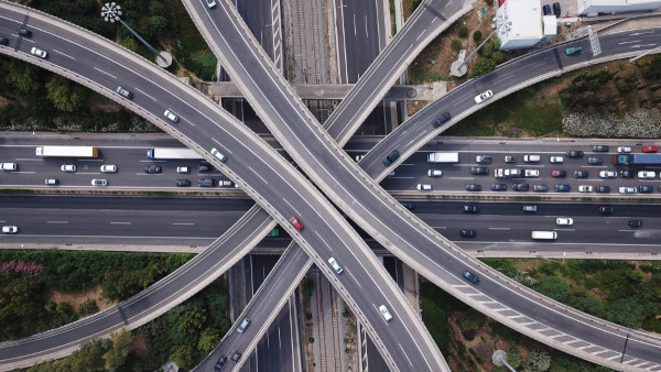 Foto aérea do interligamento de rodovias em região urbana, um exemplo de infraestrutura de transporte.