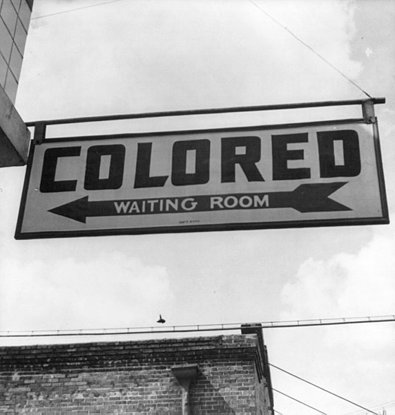 Placa indicando uma sala de espera específica para negros, no contexto da segregação racial nos Estados Unidos.