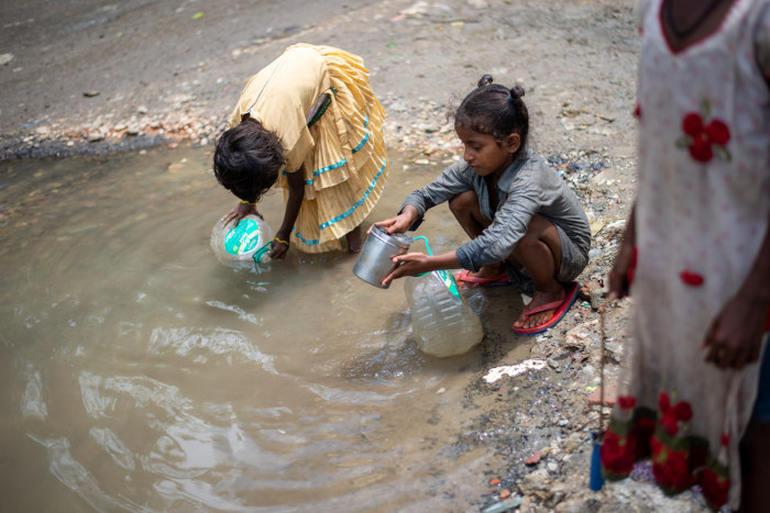 Crianças coletando água suja, exemplo da falta de saneamento básico.