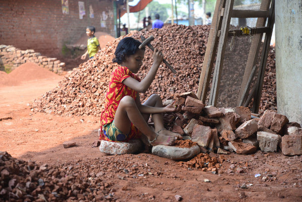 Crianças trabalhando em um depósito de desmantelamento de tijolos, um exemplo de trabalho infantil.