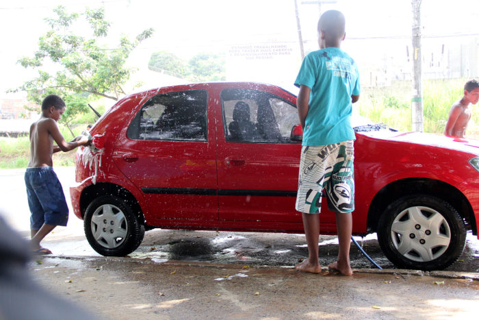 Crianças lavando um carro em um lava a jato, um exemplo de trabalho infantil no Brasil.