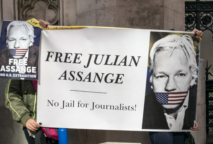 Manifestantes segurando cartaz com pedido de liberdade de Julian Assange, que estava em asilo político.