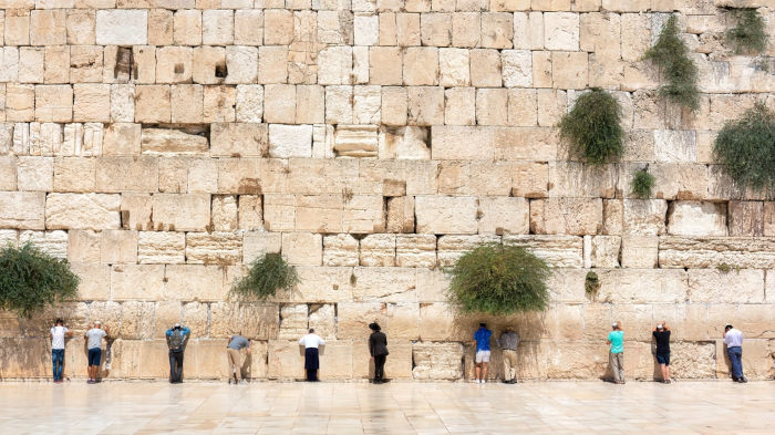 Pessoas orando em frente ao Muro das Lamentações, local sagrado para os judeus.