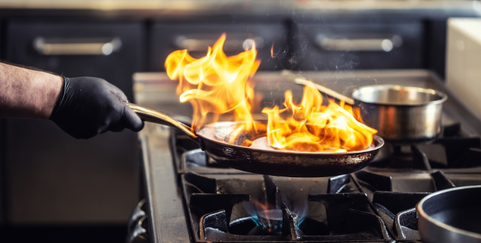 Pessoa preparando alimento com uso do fogo, cujo aquecimento ocorre pela propagação de calor estudada na calorimetria.