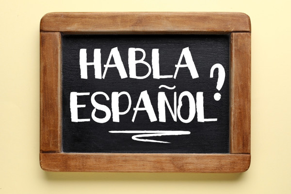 Placa com a pergunta “Habla espanhol”, com um dos verbos mais usados.