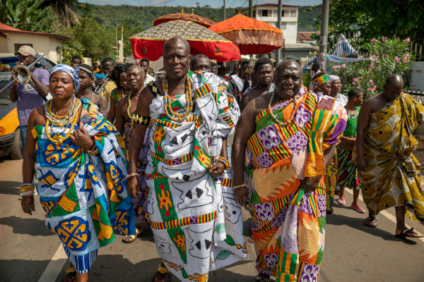 Homens e mulheres vestidos com kente, tecido colorido típico da cultura africana.