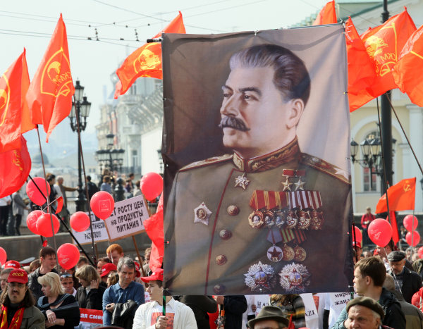 Bandeira com imagem de Josef Stalin sendo segurada por participantes de uma passeata soviética.