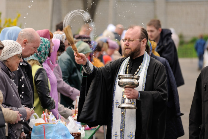 Bispo da Igreja Ortodoxa aspergindo água sobre fiéis.
