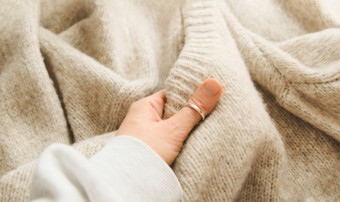 Mulher atritando sua mão com uma coberta de lã, situação que pode ser observada de acordo com a série triboelétrica.